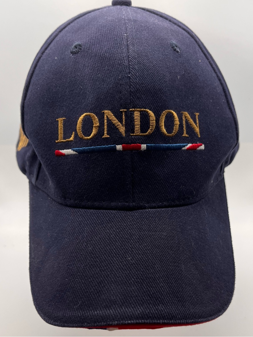 Navy “London” baseball cap w embroidered golden lion crest. Amberjack under bill